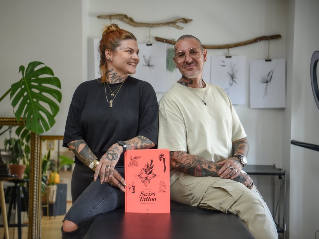Sandy Botteron et Pat Boyer dans leur studio de tatouage, avec le livre "Swiss Tattoo".