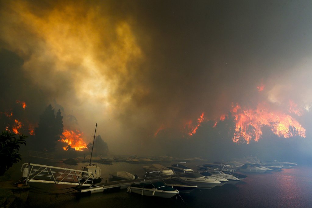 epa03846502 A forest fire burns close to boats at a marina on Sousa river in Gondomar, north of Portugal, 01 September 2013. Some 132 firemen, 36 land vehicles, a helicopter and 5 airplanes are trying to extinguish the fire.  EPA/JOSE COELHO