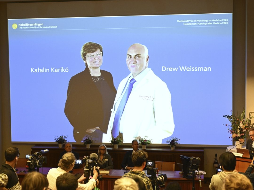 Thomas Perlmann, secrétaire de l'Assemblée du Nobel (d.) annonce à Stockholm les gagnants du prix Nobel de médecine 2023: Katalin Karikó and Drew Weissman, visibles sur l'écran.