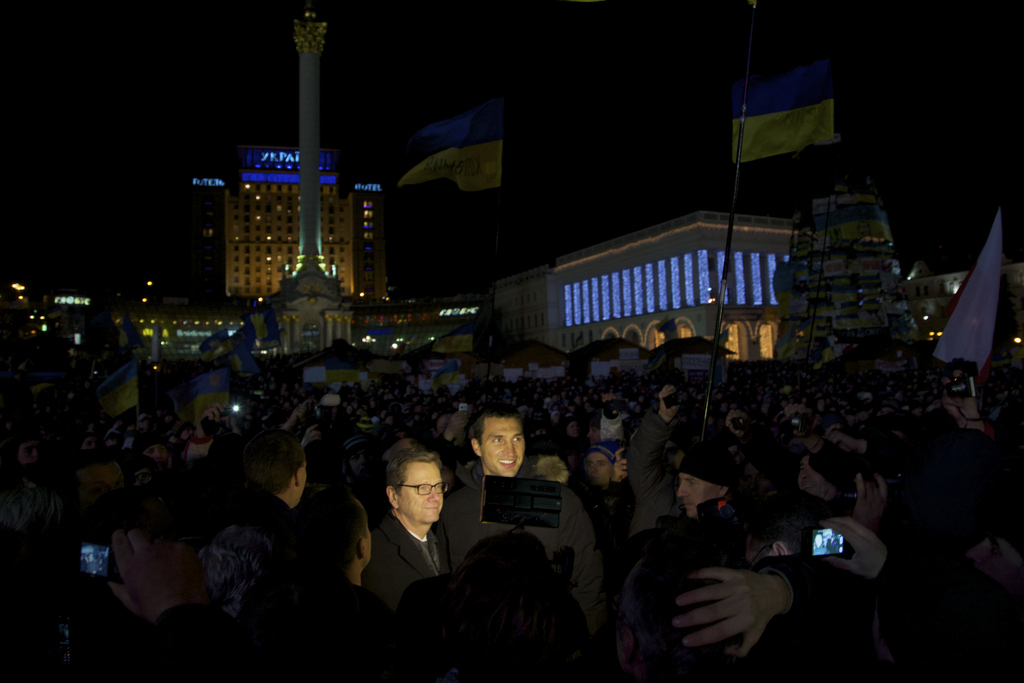 German Foreign Minister Guido Westerwelle, center left, and IBF, WBO and WBA heavyweight boxing world champion Wladimir Klitschko, center right, are lit by camera lights as they stand at the central Independence square in Kiev, Ukraine, Wednesday, Dec. 4, 2013. A resolution to Ukraine?s political turmoil remained elusive as thousands of people continued rallying on Kiev?s Independence Square and besieging key government buildings. (AP Photo/Ivan Sekretarev)