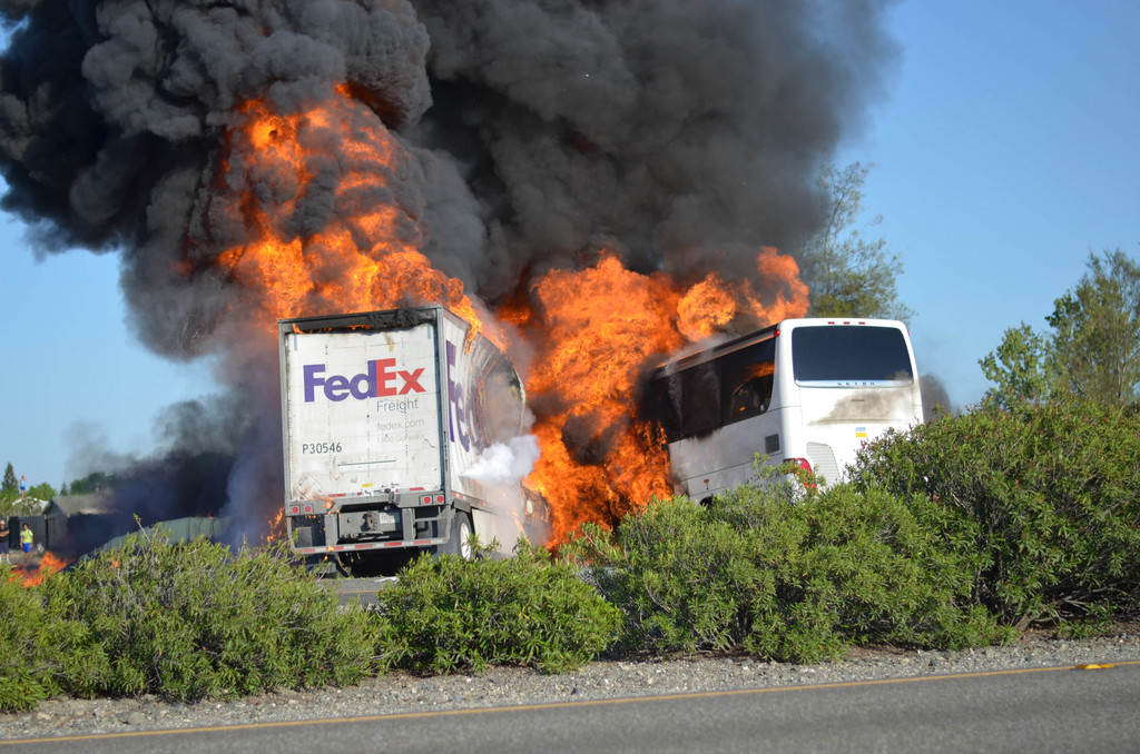 Massive flames are seen devouring both vehicles just after the crash, and clouds of smoke billowed into the sky  Thursday April 10, 2014 until firefighters had quenched the fire, leaving behind scorched black hulks of metal. The FedEx tractor-trailer crossed a grassy freeway median in Northern California and slammed into the bus carrying high school students on a visit to a college. At least nine were killed in the fiery crash, authorities said. (AP Photo/Jeremy Lockett)
