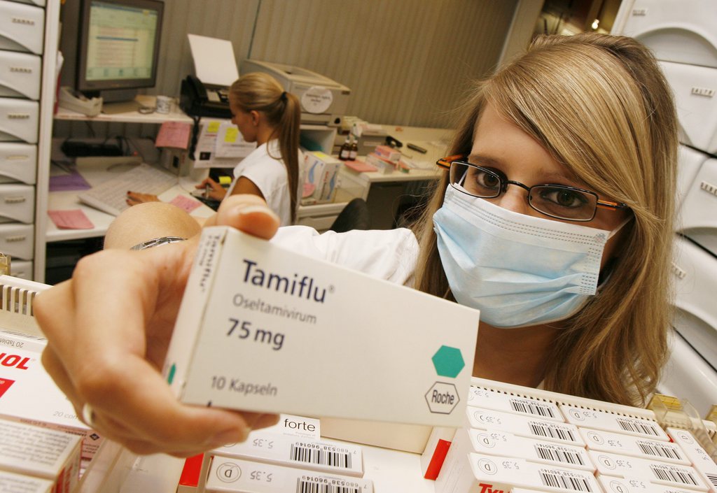 GESTELLTES BILD - Pharmaassistentin Selina traegt einen Mundschutz waehrend sie eine Schachtel des Grippemittels Tamiflu haelt, am Freitag, 24. Juli 2009, in der Rike Apotheke in Effretikon. (KEYSTONE/Steffen Schmidt)