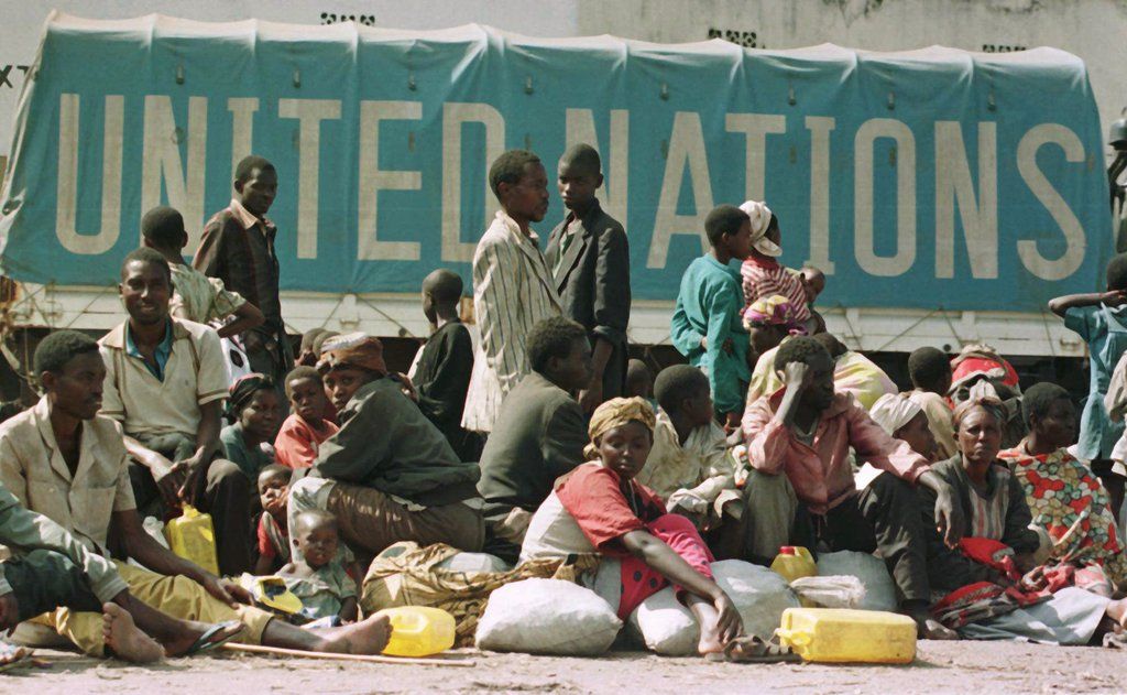 Rwandan refugees await at the Gisenyi market for transport to Kigali as a U.N. truck drives behing them Sunday Nov. 24, 1996. Lawmakers are meeting in Stuttgart, Germany to decide the fate of an international peace keeping force that would assist refugees in their plight. (AP PHOTO/Jerome Delay)