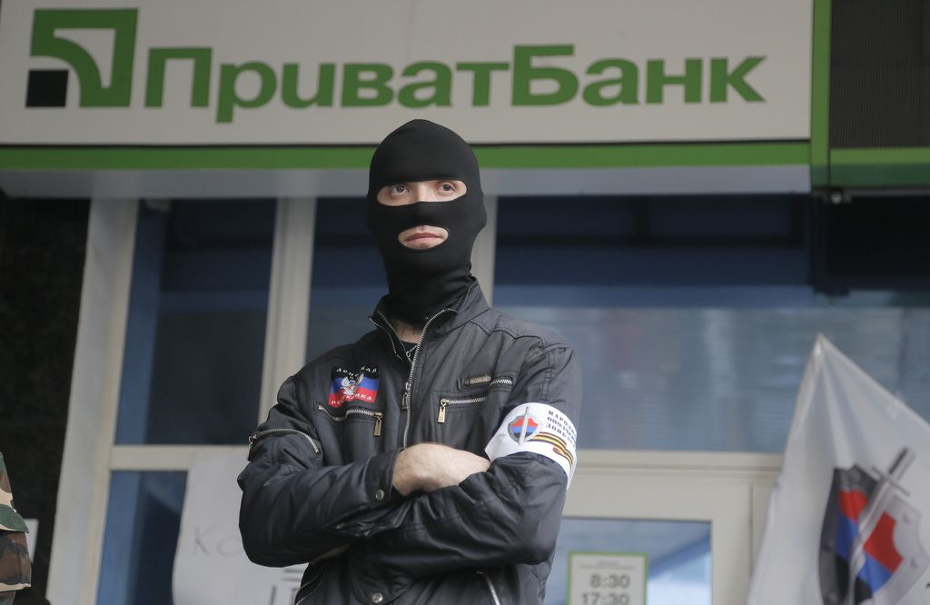 A masked pro-Russian activist block the office of a "Privatbank" bank, owned by a businessman who is considered to back the new pro-western government in Donetsk, Ukraine, Monday, April 28, 2014. Ukraine's acting government and the West have accused Russia of orchestrating the unrest, which they fear Moscow could use as a pretext for an invasion. (AP Photo/Efrem Lukatsky)