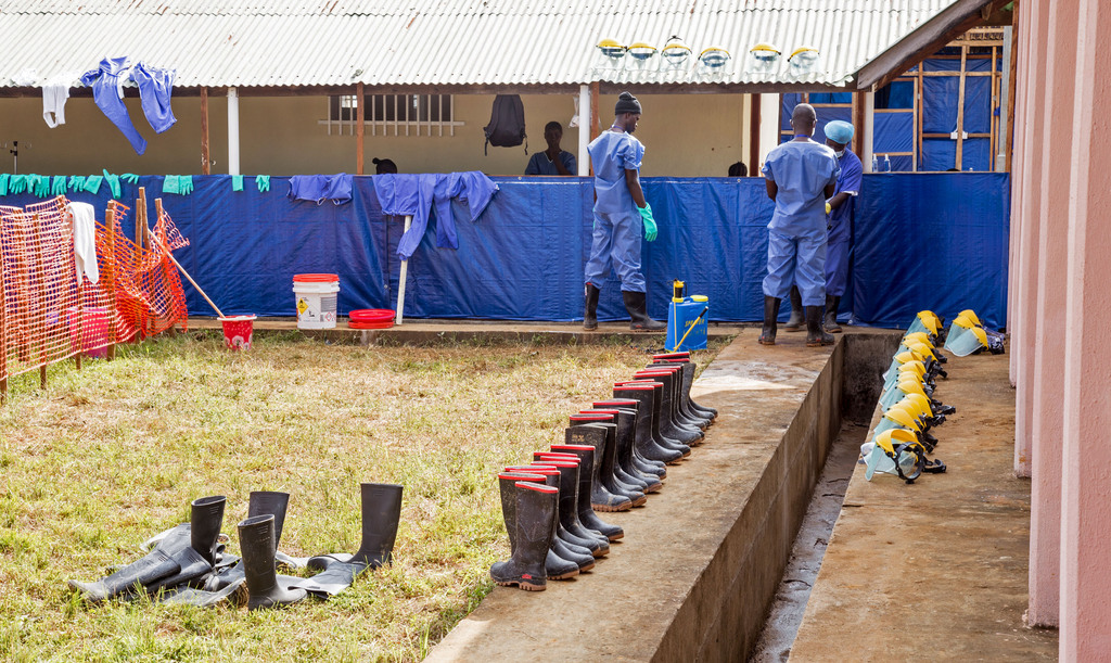 Healthcare workers, rear, clean Ebola virus prevention gear at the Hastings Police training school, used as a Ebola virus treatment center with over a hundreds beds  in the village of Hastings, Sierra Leone, Saturday, Sept. 20, 2014. Some in Sierra Leone ran away from their homes Saturday and others clashed with health workers trying to bury dead Ebola victims as the country struggled through the second day of an unprecedented lockdown to combat the deadly disease. (AP Photo/ Michael Duff)