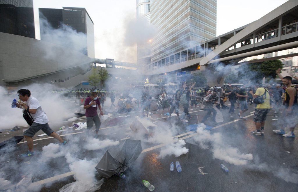 epa04421572 Hong Kong police fire tear gas at pro-democracy protesters during the first day of the mass civil disobedience campaign Occupy Central, Hong Kong, China, 28 September 2014. Thousands of pro-democracy demonstrators surrounded central government offices and blocked major streets in Hong Kong on Sunday to protest China's decision to restrict open elections in the territory. The protests followed a decision last month by China's top legislative body to restrict the nominations for chief executive in 2017. The candidate who wins the popular vote would have to be formally appointed by the central government before taking office.  EPA/ALEX HOFFORD
