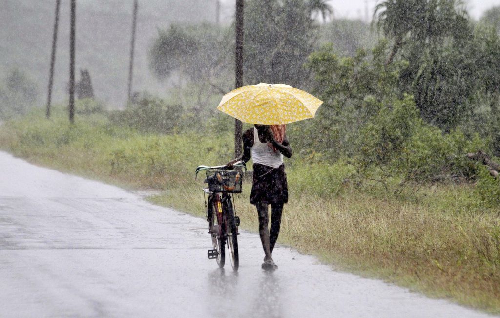 An Indian man holds an umbrella to protect himself from the heavy rains near Gopalpur, in Ganjam district, 140 kilometers (87 miles) south of Bhubaneswar, India, Saturday, Oct. 11, 2014. The India Meteorological Department described Cyclone Hudhud as a "very severe" storm that could pack winds of 195 kilometers (120 miles) per hour and cause torrential rains when it makes landfall near the port city of Visakhapatnam around noon Sunday. (AP Photo/Biswaranjan Rout)