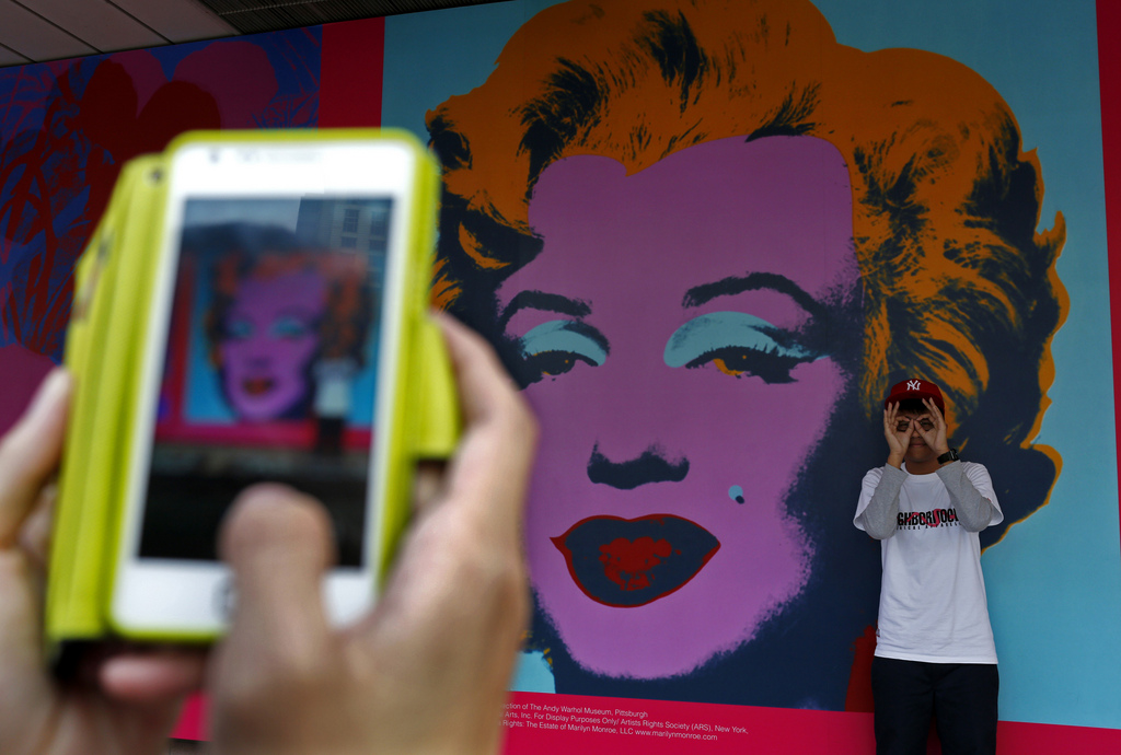 A man poses at the entrance to Hong Kong Art Museum which is decorated with Andy Warhoi's works during an exhibition in Hong Kong Sunday, Jan. 27, 2013. The exhibition will bring the largest ever collection of Warhol's works to Asia. (AP Photo/Vincent Yu)