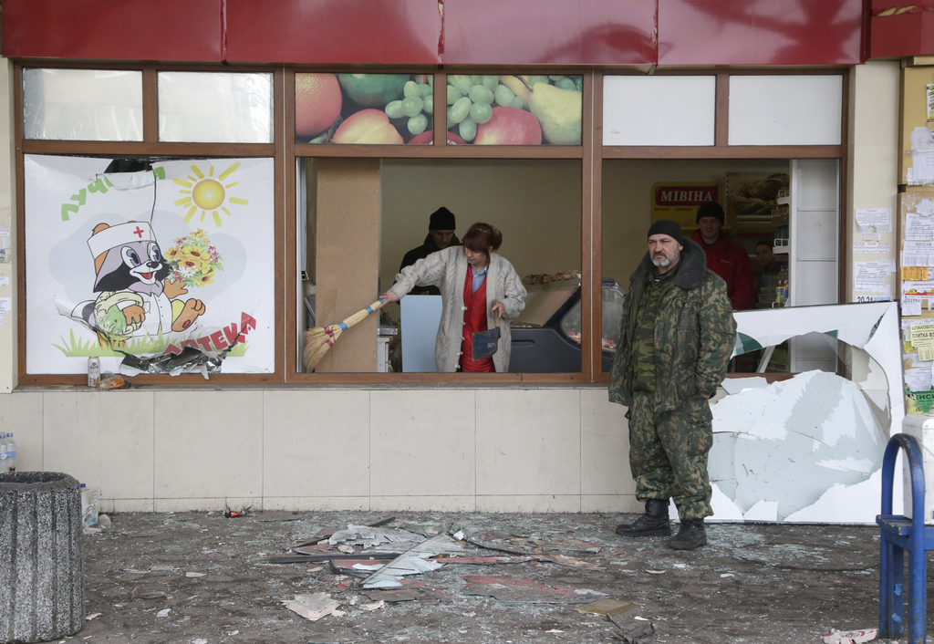 A woman cleans shattered glass after a shop was damaged when a bus station was hit during the recent shelling between Russian-backed separatists and Ukrainian government forces in Donetsk, Ukraine, Wednesday, Feb. 11, 2015. This is at least the third time a bus has been hit in the rebel stronghold but the first time it happens so close to the center, an area of the city which has so far been mostly spared the destruction. (AP Photo/Petr David Josek)
