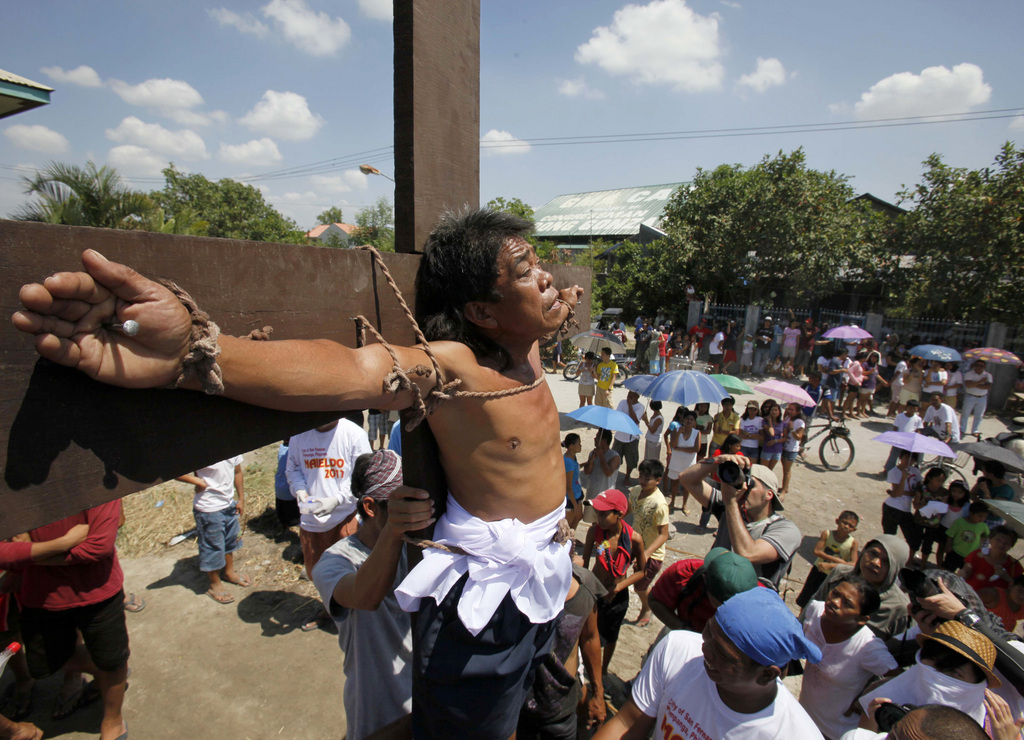 A crowd watches as Alex Laranang takes part in the crucifixion of Jesus Christ on Good Friday at San Juan village, San Fernando city, Pampanga province, northern Philippines, Friday, April 22, 2011. Several Filipinos were nailed to wooden crosses Friday to reenact Jesus Christ's suffering in an annual rite that has been rejected by Catholic church leaders but draws thousands of tourists on Good Friday. (AP Photo/Bullit Marquez)