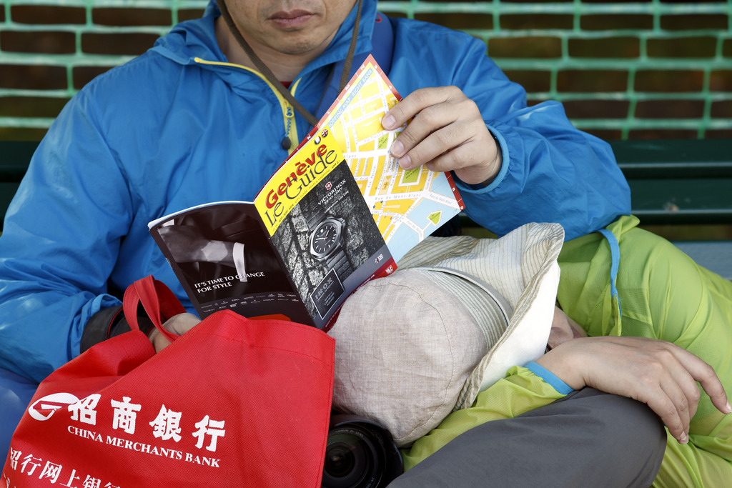 A Chinese tourist reads the "Geneve le Guide" sitting on a bench near the Geneva lake, in Geneva, Switzerland, Saturday, September 20, 2014. (KEYSTONE/Salvatore Di Nolfi)