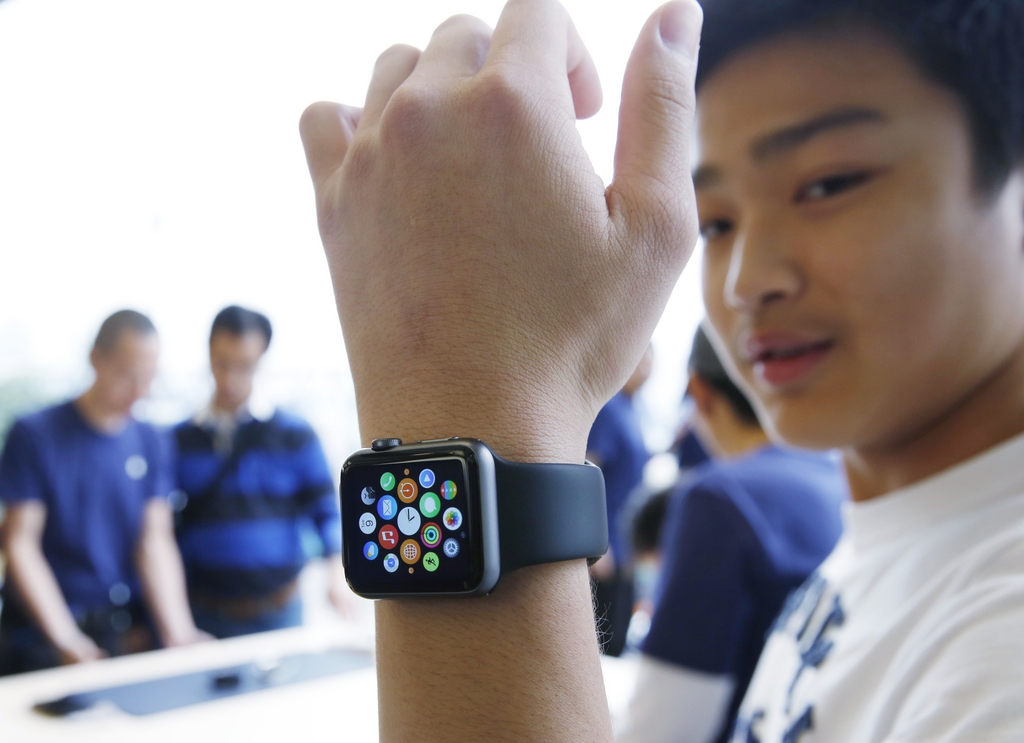 In this April 10, 2015, photo, a customer tries on an Apple Watch at an Apple Store in Hong Kong. From Beijing to Paris to San Francisco, the Apple Watch made its debut Friday. Customers were invited to try them on in stores and order them online. (AP Photo/Kin Cheung, File)