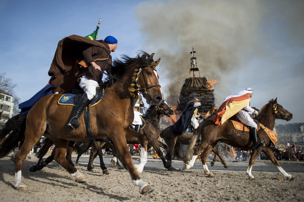 Reiter einer Zunft galoppieren um den brennenden Boeoegg, anlaesslich des traditionellen Sechselaeutens am Montag, 13. April 2015, in Zuerich. (KEYSTONE/Ennio Leanza)....Members of a guild ride around the "Boeoegg" on the Sechselaeuten place in Zurich, Switzerland, pictured on April 13, 2015. The Sechselaeuten (ringing of the six o'clock bells) is a traditional end of winter festival with a parade of guilds in historical uniforms on horseback and the burning of the Boeoegg, a symbolic snowman, at 6 pm. The faster the Boeoegg explodes, the hotter the summer will be according to traditional weather rules. (KEYSTONE/Ennio Leanza)..