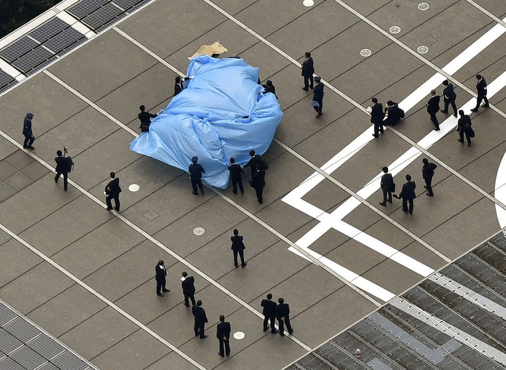Investigators gather around a small drone covered with blue sheets, on the roof of Prime Minister Shizo Abe's official residence in Tokyo Wednesday, April 22, 2015.  Japanese authorities were investigating Wednesday after the small drone reportedly containing traces of radiation was found on the roof of the prime minister's office, sparking concerns about drones and their possible use for terrorist attacks.  (Tsuyoshi Ueda/Kyodo News via AP) JAPAN OUT, MANDATORY CREDIT