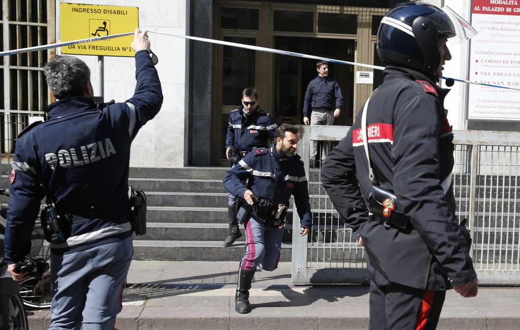 Policemen run out of the tribunal building in Milan, Italy, after a shooting was reported inside a courtroom Thursday, April 9, 2015. (AP Photo/Luca Bruno)