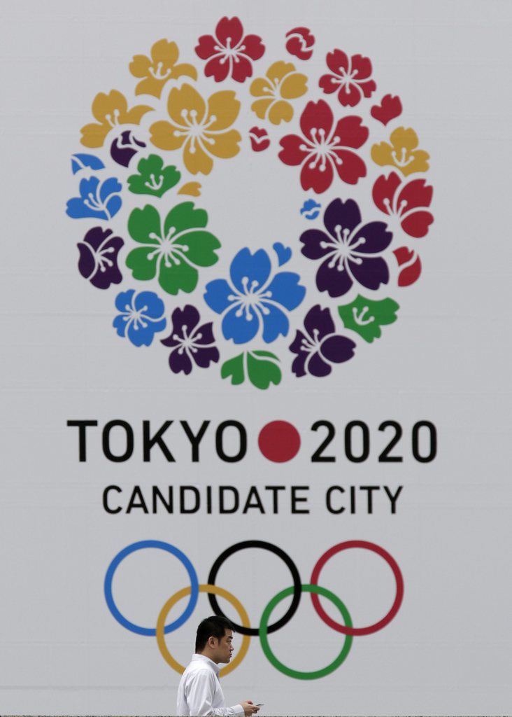 epa03853405 A businessman walks past the huge emblem of Tokyo's bidding to host 2020 Olympic Games at its headquarters in Tokyo, Japan, 06 September 2013. Tokyo and Japan wait for the International Olympic Committee's decision on Tokyo's bid to host the 2020 Olympic Games. The decision will be announced in the early morning on 08 September (evening of 07 September in Buenos Aires) in the Japanese capital as it is waiting for the decision with other can date cities of Istanbul and Madrid for the 2020 Olympics.  EPA/KIMIMASA MAYAMA