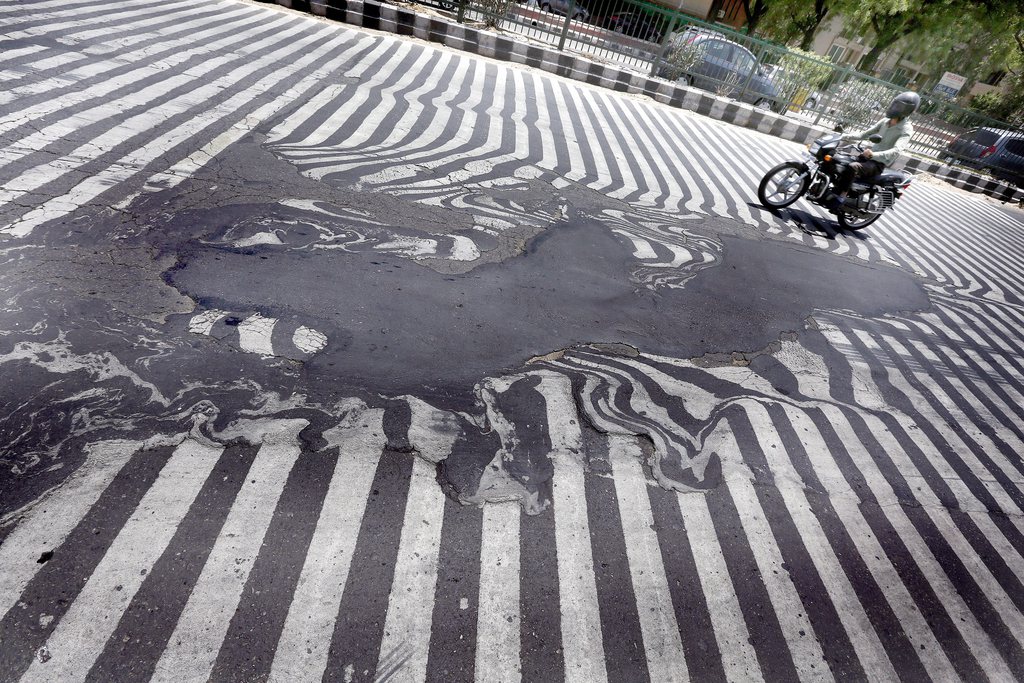 epa04769719 Road markings appear distorted as the asphalt starts to melt due to the high temperature in New Delhi, India, 27 May 2015. More than 1,150 people are reported dead from a heat wave sweeping across south India and Andhra Pradesh state was the worst hit, where 884 people had died of heatstroke since 18 May. Weather officials said northwesterly dry and hot winds from the desert state of Rajasthan were responsible.  EPA/HARISH TYAGI