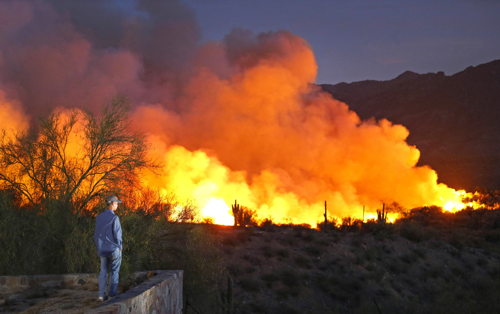 Justin Winsor watches a wildfire from the Breezeway Trailer Park Wednesday, June 17, 2015 in Kearny, Ariz.  The blaze is not contained at all, but it's mostly relegated to a riverbed and about 200 firefighters have kept it burning away from the town of 2,000 residents, officials said.  (David Kadlubowski/The Arizona Republic via AP)  MARICOPA COUNTY OUT; MAGS OUT; NO SALES; MANDATORY CREDIT