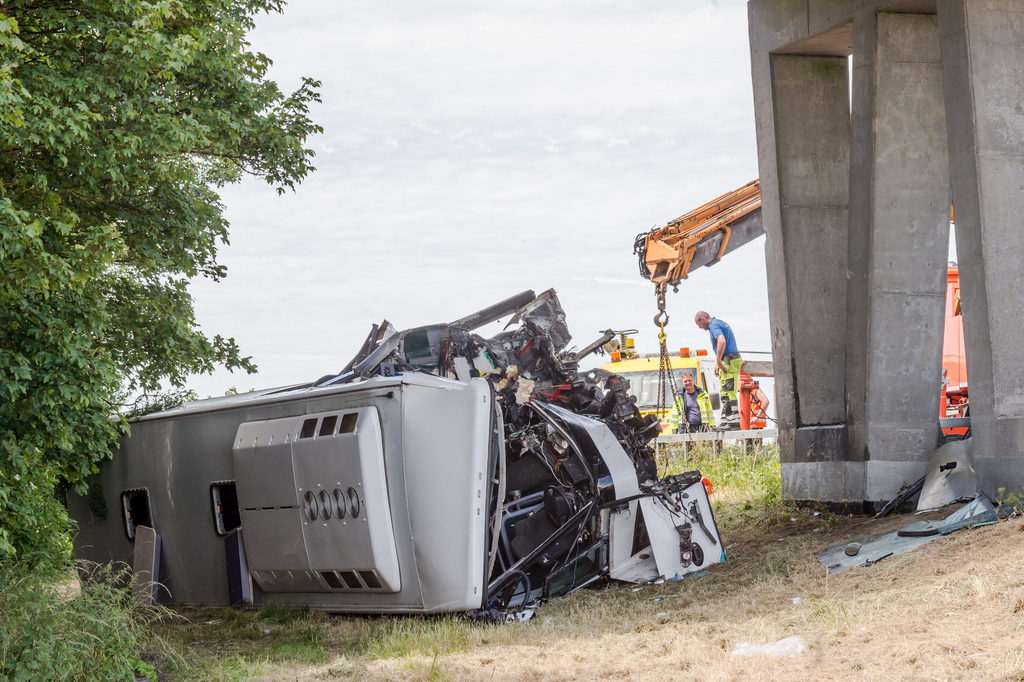 Safety workers attend to a bus which crashed on a motorway in Middlekerke, Belgium on Sunday, June 28, 2015. The bus, carrying British schoolchildren went off the highway and overturned near the Belgian coast on Sunday, injuring the driver and some of the children and killing one of the adults accompanying them. (AP Photo/Geert Vanden Wijngaert)