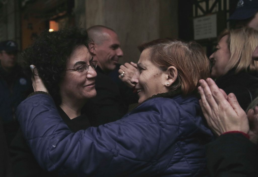 Cleaning workers, laid off by the Finance Ministry, hug new Deputy Finance Minister Nadia Valavani, left, and the new Greek Finance Minister Yanis Varoufakis, background, outside the National Economy Ministry in Athens, on Wednesday, Jan. 28, 2015. Varoufakis announced that the government will re-hire them to the public sector. Dozens of the nearly 600 formerly state-employed cleaning ladies, who were sacked 18 months ago amid austerity cuts, have kept up the protest against their dismissals for more than eight months. Their court battle became a symbol of anti-austerity protests in Greece. (AP Photo/Lefteris Pitarakis)
