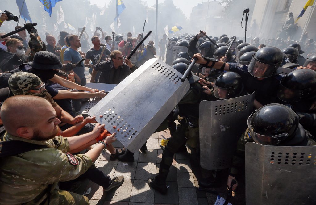 epa04906425 Opponents of changes to Ukrainian Constitution clash with police in front of Ukrainian Parliament in Kiev, Ukraine, 31 August 2015 as lawmakers accepted the project to changing Ukrainian Constitution about decentralization of power in first reading. A grenade exploded outside Ukraine's parliament 31 August during a protest as legislators voted in favour of a draft law to give special status to the eastern regions that are locked in a conflict between the Ukrainian military and pro-Russian separatists. Local media reports said that the grenade was thrown into a cordon of police and national guardsmen in Kiev. Dozens of people were reportedly injured.  EPA/SERGEY DOLZHENKO