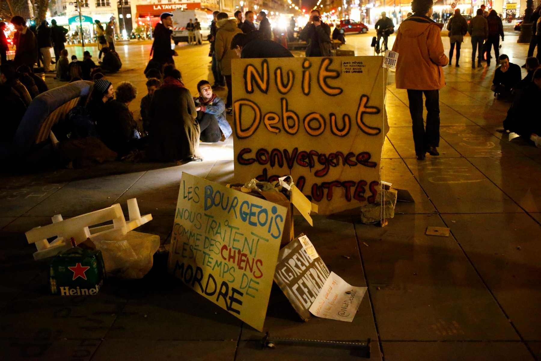 People gather near a banner reading"Nuit Debout" or "Rise up at Night," "The conservative bourgeois treat us like dogs, it is time to bite" on the Place de la Republique in Paris, France, Monday, April 4, 2016. A few hundred protesters have been camping out, holding night-time demonstrations since last week at a symbolic rallying point on the Place de la Republique, to express anger at a proposed labor law that would extend the workweek and make layoffs easier. The social media-driven movement, called "Nuit Debout" or "Rise up at Night," sprang from nationwide strikes and protests Thursday. (AP Photo/Francois Mori) France Rise up at Night
