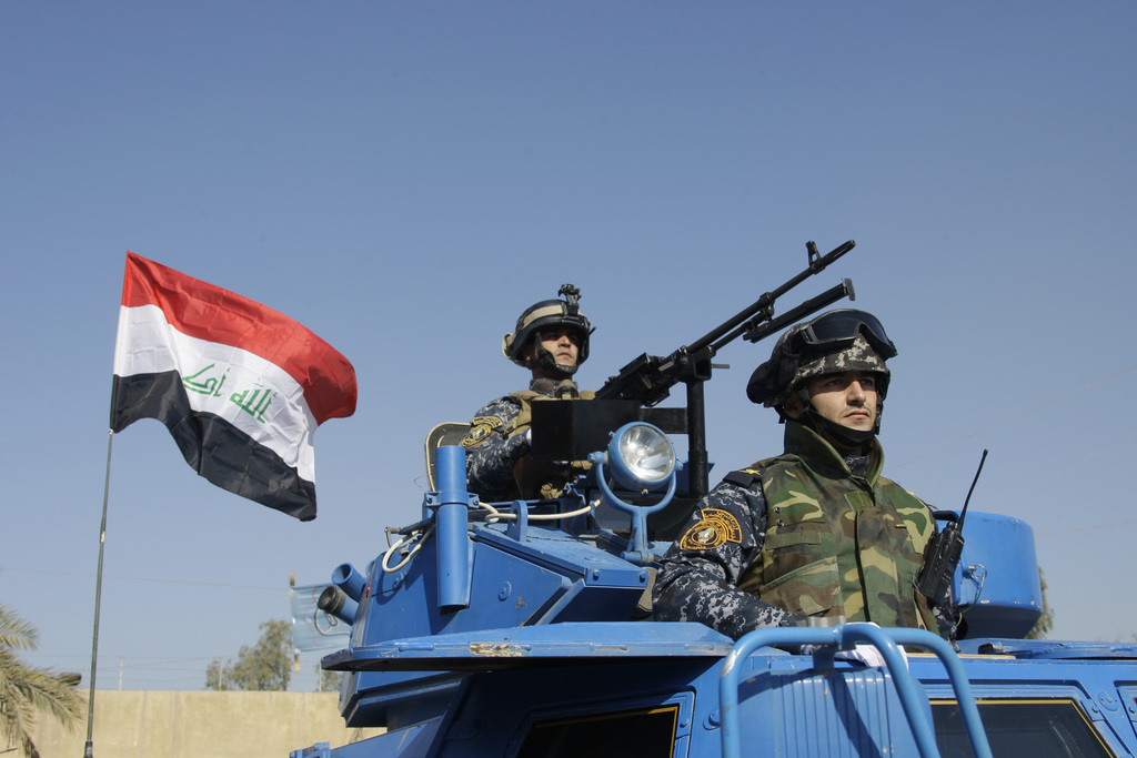 Le drapeau irakien flottent derrière des représentants de l'ordre à Bagdad.