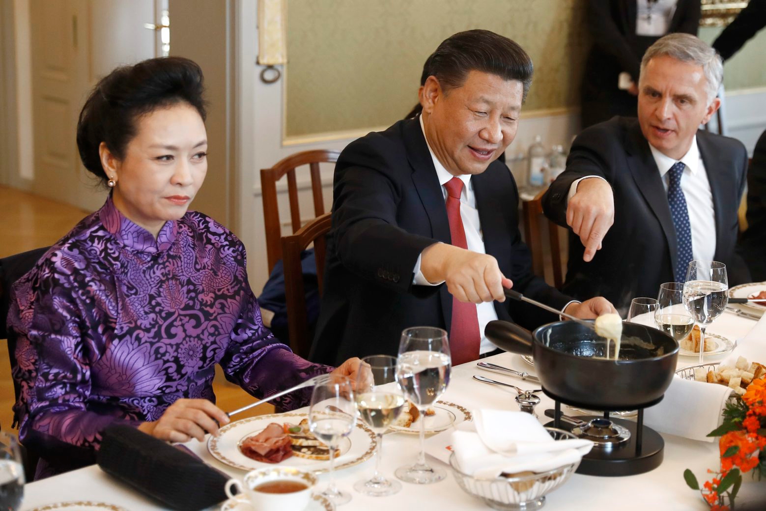 China's President Xi Jinping, center, Xi's wife Peng Liyuan, left, and Swiss Foreign Minister Didier Burkhalter eat Swiss cheese fondue during lunch during Xi's two days state visit to Switzerland in Bern, Switzerland, Monday, January 16, 2017. (KEYSTONE/POOL/Peter Klaunzer) SWITZERLAND CHINA STATE VISIT