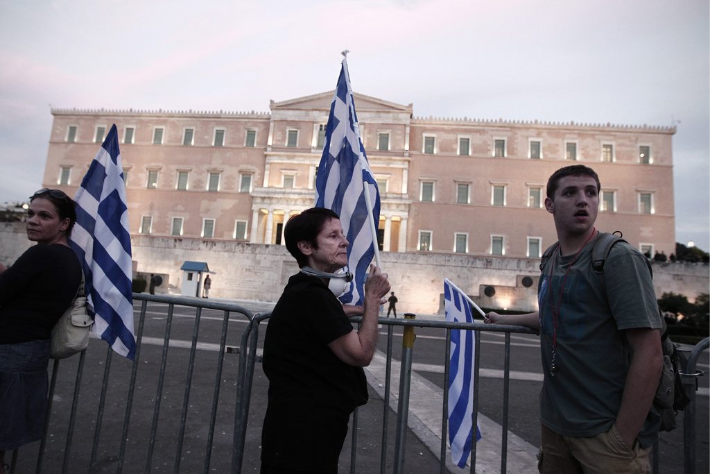 epa03425993 Demonstrators hold Greek flags during a protest in front of the Parliament building against new austerity measures, in Athens, Greece, 08 October 2012. The protest, called by trade unions, took place one day ahead the visit of German Chancellor Angela Merkel in Athens.  EPA/ALKIS KONSTANTINIDIS