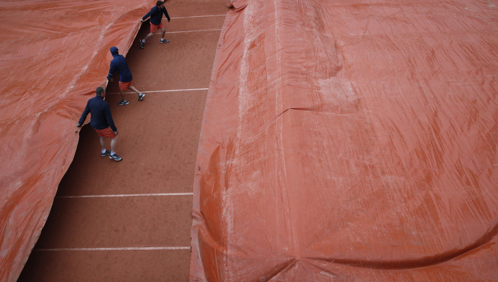 Les employés du stade bâchent les courts de Roland-Garros.