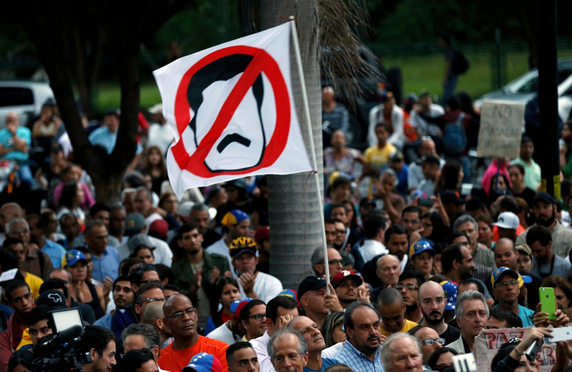 An anti-government demonstrator waves a flag against Venezuela's President Nicolas Maduro during a vigil in honor of those who have been killed during clashes between security forces and demonstrators in Caracas, Venezuela, Monday, July 31, 2017. Many analysts believe Sunday's vote for a newly elected assembly that will rewrite VenezuelaÄôs constitution will catalyze yet more disturbances in a country that has seen four months of street protests in which at least 125 people have died. (AP Photo/Ariana Cubillos) Venezuela Political Crisis