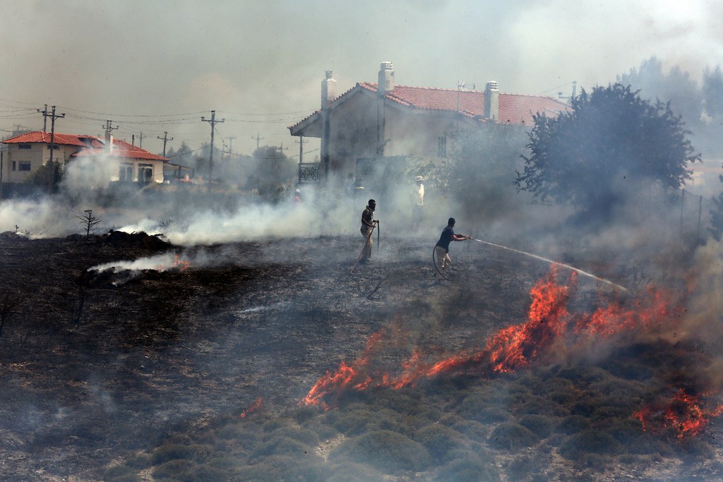 Les pompiers tentent d'éteindre un incendie qui brûle dans une forêt près du village de Kalamos, à 50 km au nord d'Athènes.