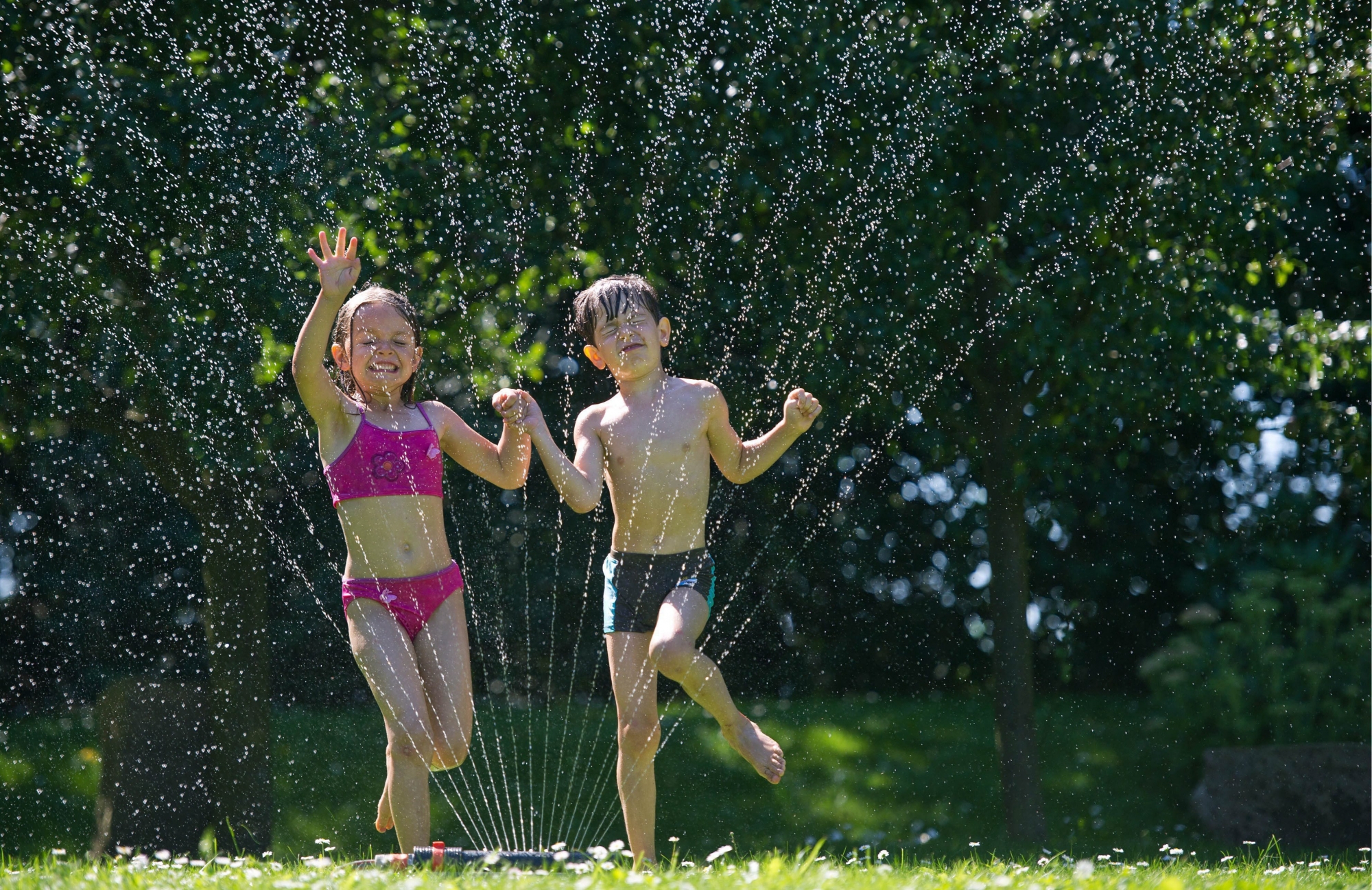 epa03365281 Amy and Jannik jump through the water fountain of a lawn sprinkler in a garden in Sieversdorf, Germany, 19 August 2012. Meteorologists predict this weekend to be the hottest of the year so far with temperatures reaching some 38 degrees celsius.  EPA/PATRICK PLEUL GERMANY WEATHER