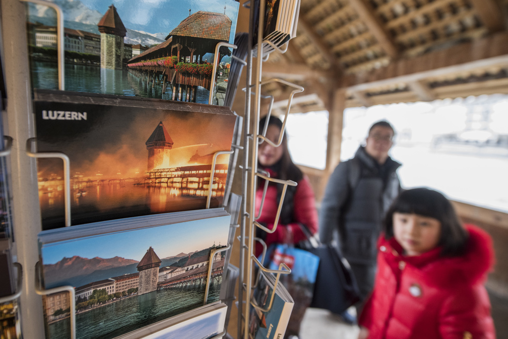 Des touristes asiatiques s'arrêtent pour regarder les cartes postales du Kapellbrücke de Lucerne. (Illustration)