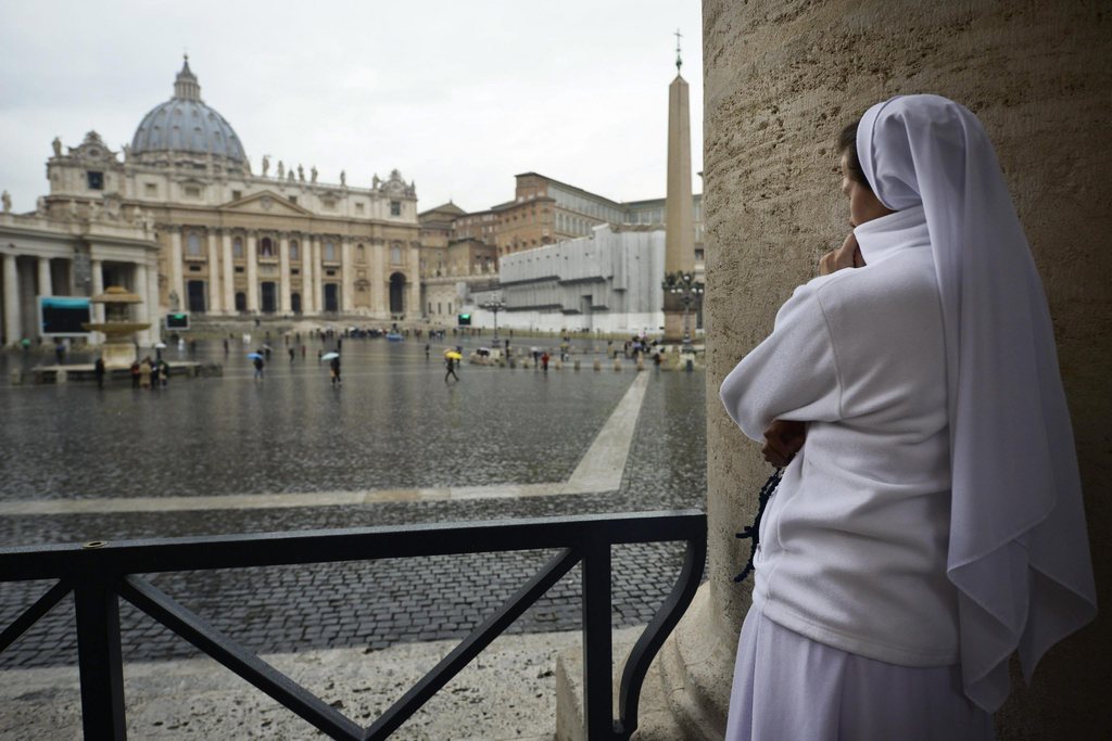 epa03621359 A nun prays in front of Saint Peter's Basilica while security makes strict controls during the second day of the Conclave at the Vatican 13 March 2013. The Catholic Church's cardinal electors celebrated mass before entering the Sistine Chapel for a second round of voting Wednesday, after the first day of the papal election proved inconclusive.  EPA/CIRO FUSCO