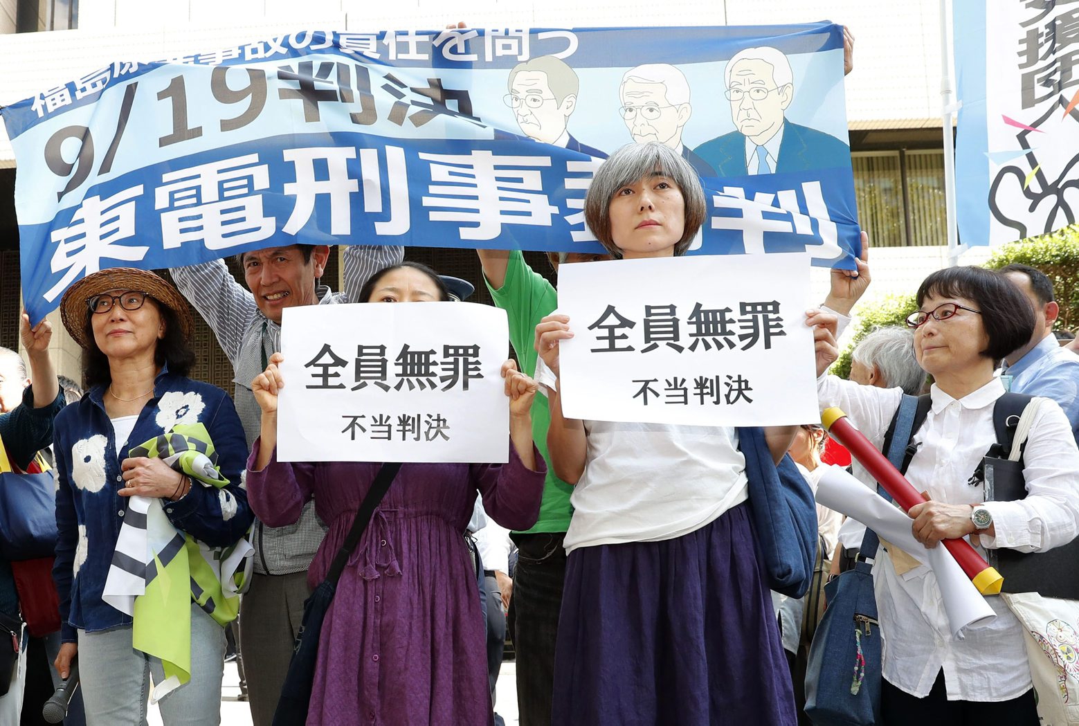 A group of supporters of the trial shows banners reading "unjust sentence" in front of Tokyo District Court in Tokyo Thursday, Sept. 19, 2019. The court on Thursday ruled that three former executives for Tokyo Electric Power Company were not guilty of professional negligence in the 2011 Fukushima meltdown. It was the only criminal trial in the nuclear disaster that has kept tens of thousands of residents away from their homes because of lingering radiation contamination. (Satoru Yonemaru/Kyodo News via AP) Japan Nuclear Disaster
