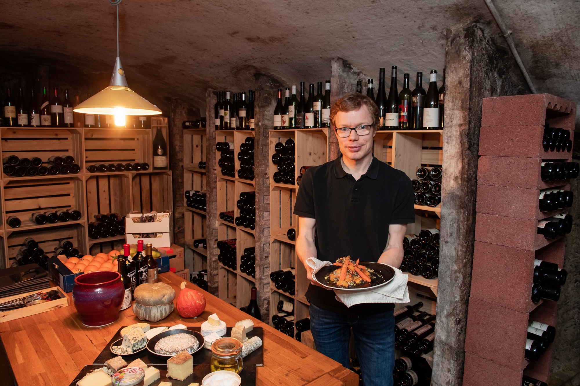 Simon Peguiron présente son plat principal dans la cave à vins et à fromages du restaurant.