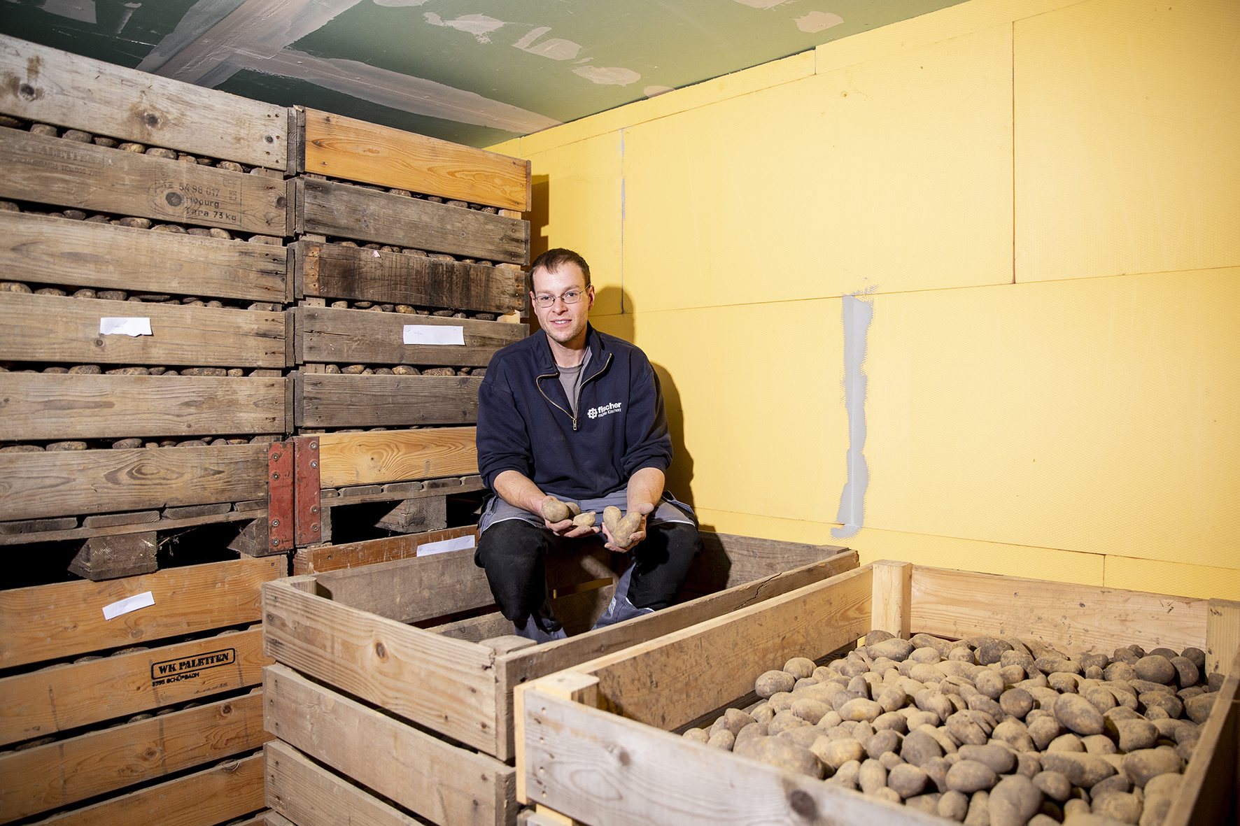 Serge Fankhauser et ses caisses où sont conservées les pommes de terre destinées à la vente directe.