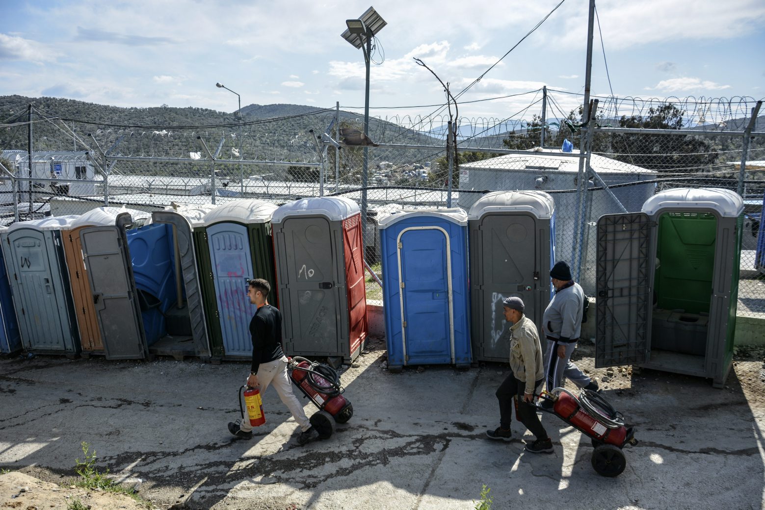 Migrants pull fire extinguishers in Moria refugee camp on the northeastern Aegean island of Lesbos, Greece, Monday, March 16, 2020. The Fire Service said a migrant, who was not further identified, was found dead inside Moria camp after the fire broke out Monday. (AP Photo/Panagiotis Balaskas) Greece Migrants